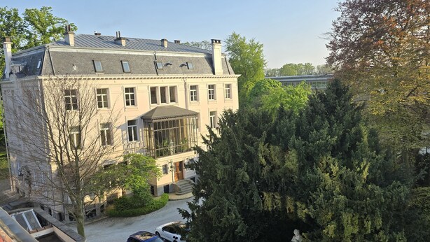 A large, historic building with a symmetrical facade, multiple windows, and a central entrance with a portico. - Fernand Cocq Elegant Residence (Brussels)
