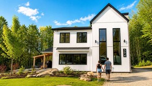 A two-story house with a covered porch, a driveway, and a well-maintained lawn. - Lake, Spa and Pool Table | Le Gaia (Chertsey)