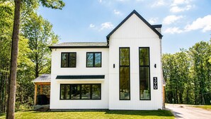 A modern two-story house with a large garage, a covered porch, and a well-maintained lawn.