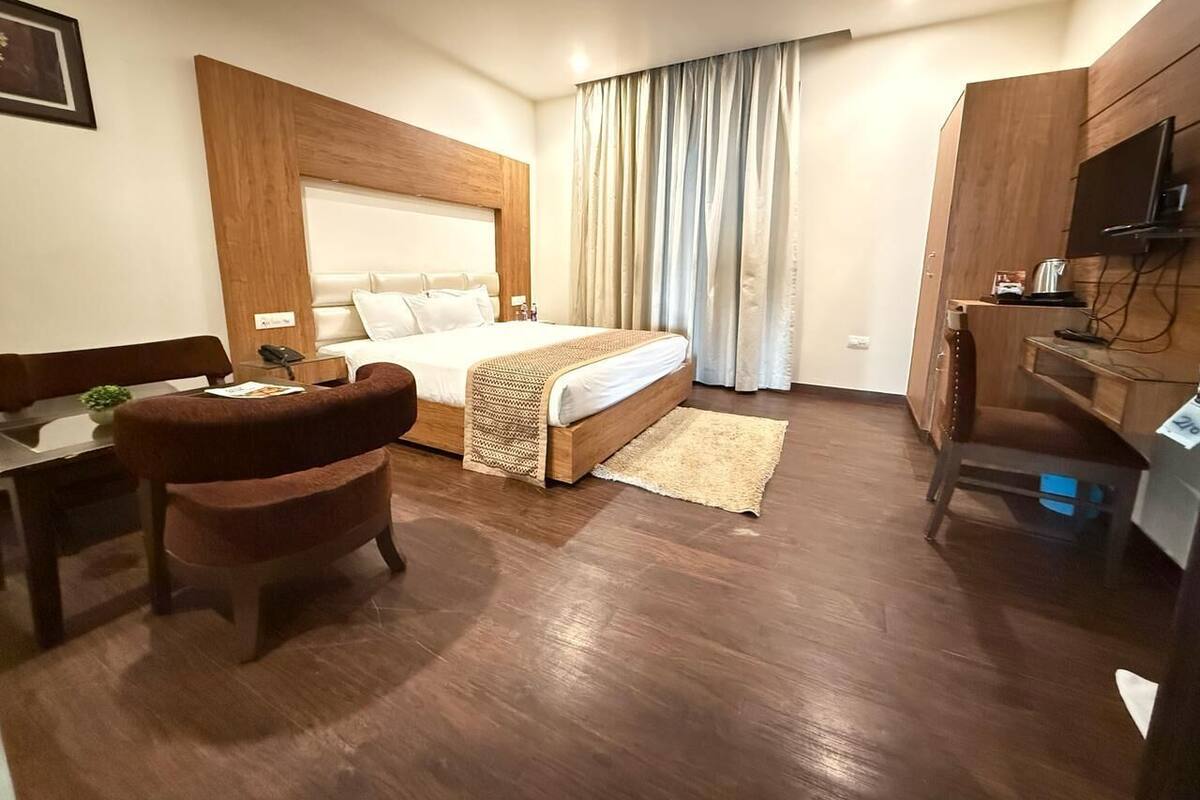A hotel room with a bed, a desk, a chair, and a television.