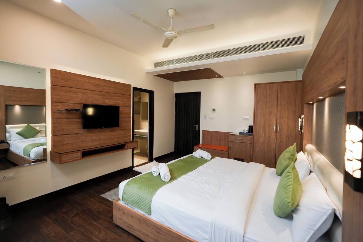 A modern hotel room with a bed, a television, a wardrobe, and a bathroom.