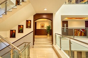 A multi-level interior with a staircase, glass railings, and framed artwork. - The Altruist Katra Hotel (Katra)