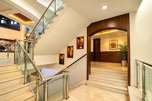 A modern hotel lobby with a glass staircase, marble flooring, and wooden accents. - The Altruist Katra Hotel (Katra)