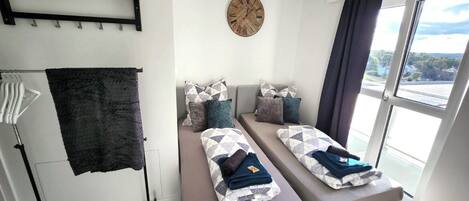 A modern room with two beds, a large window, and a view of the outdoors.