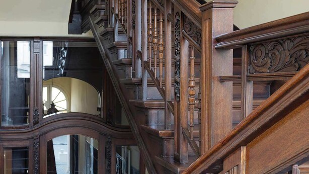 A grand wooden staircase with intricate carvings and a polished finish. - Big Premium Apartment with Rhine View, totally new (Duisburg)