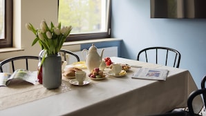 A dining table set with a teapot, cups, pastries, and a vase of flowers. - Big Premium Apartment with Rhine View, totally new (Duisburg)