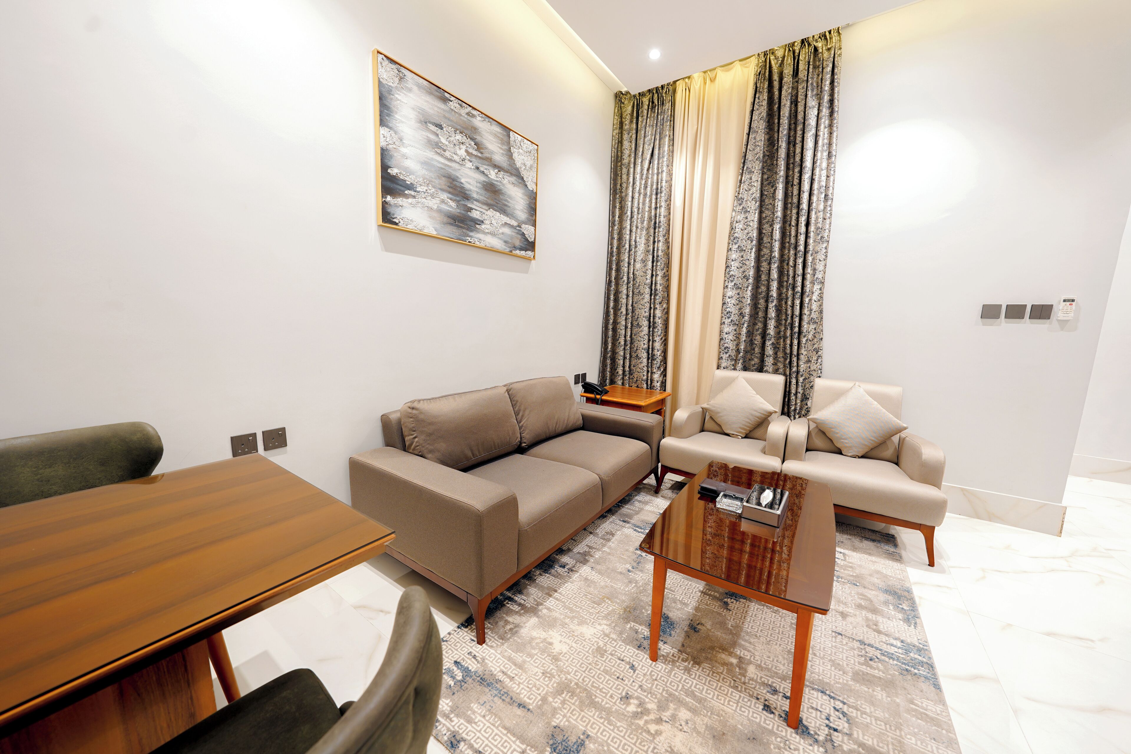 A modern living room with a wooden dining table, two sofas, a coffee table, and a patterned rug.