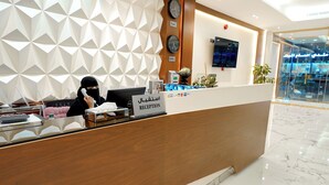 A reception desk with a geometric wall design, clocks, and a sign indicating 'RECEPTION'.