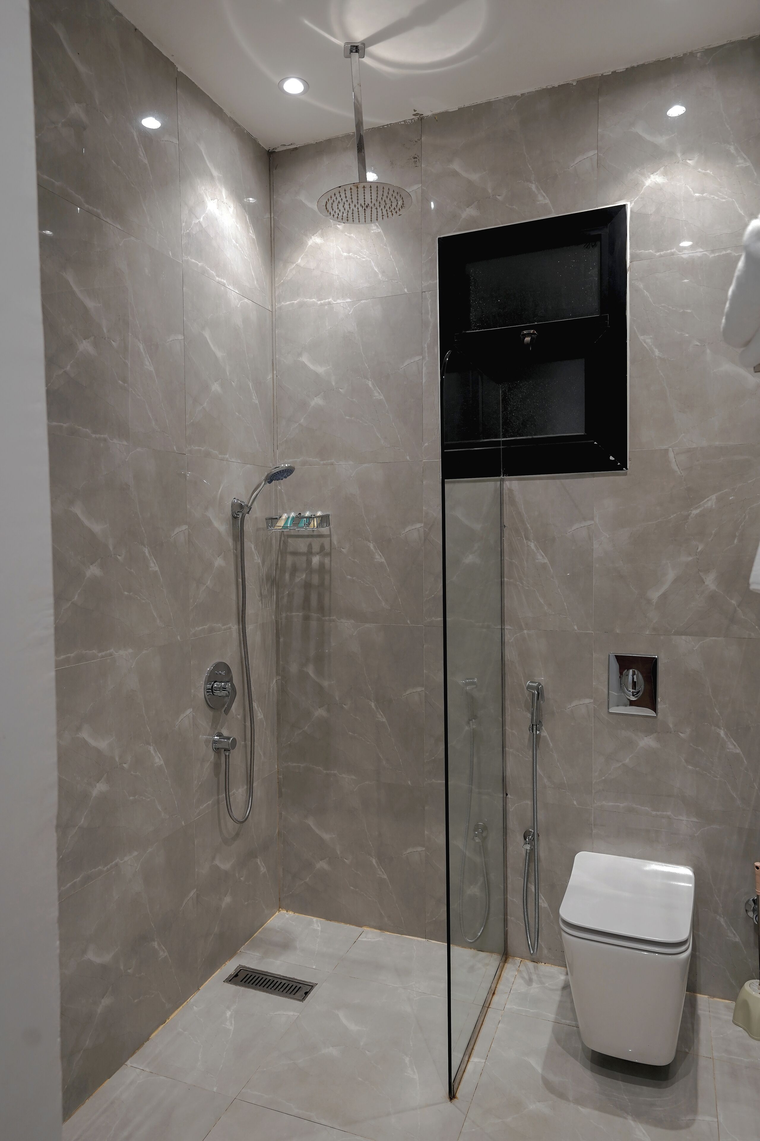 Un baño moderno con ducha envuelta en vidrio, inodoro y lavamanos integrado.