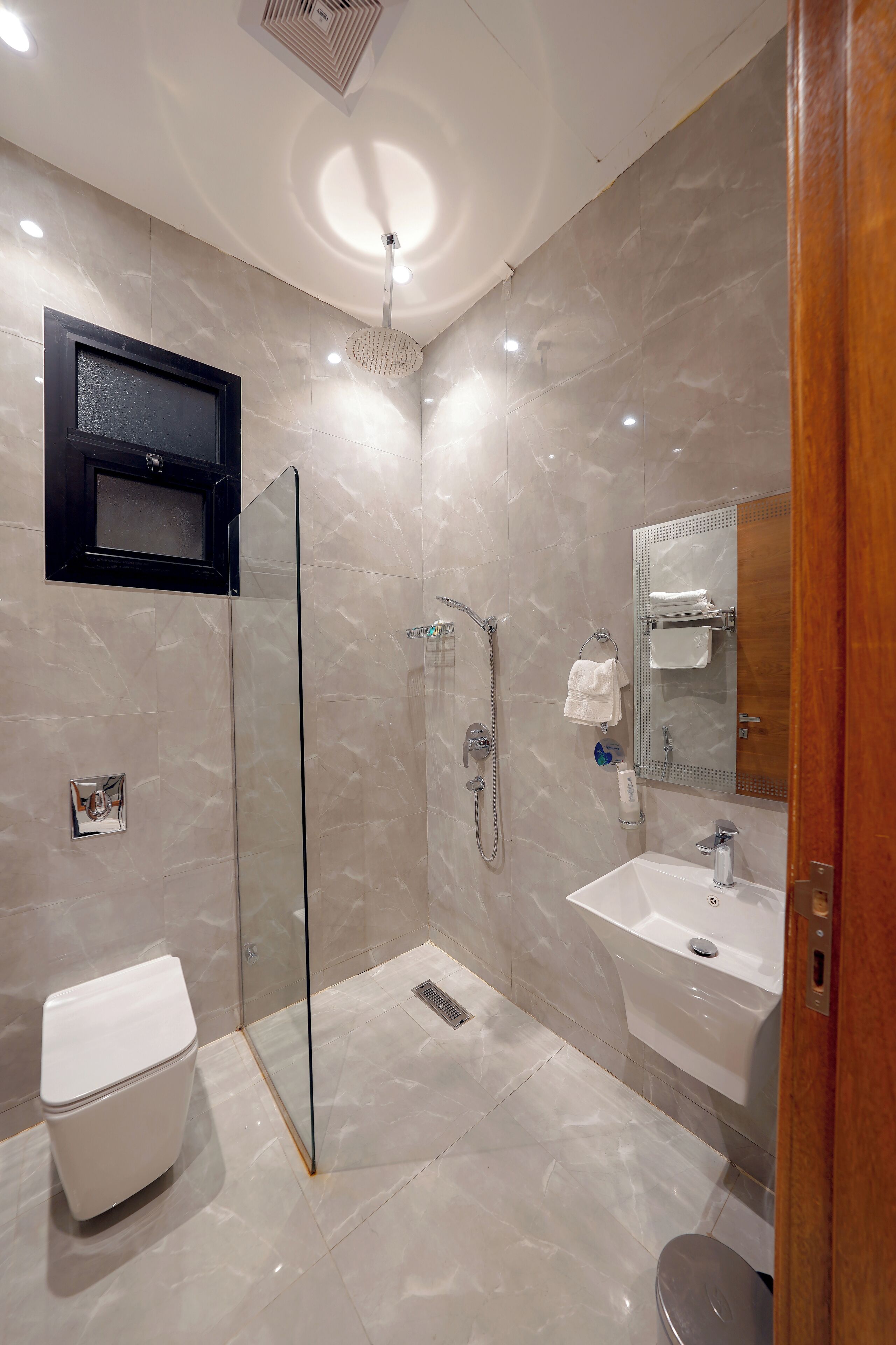 A modern bathroom with a glass shower enclosure, a white sink, and a toilet.
