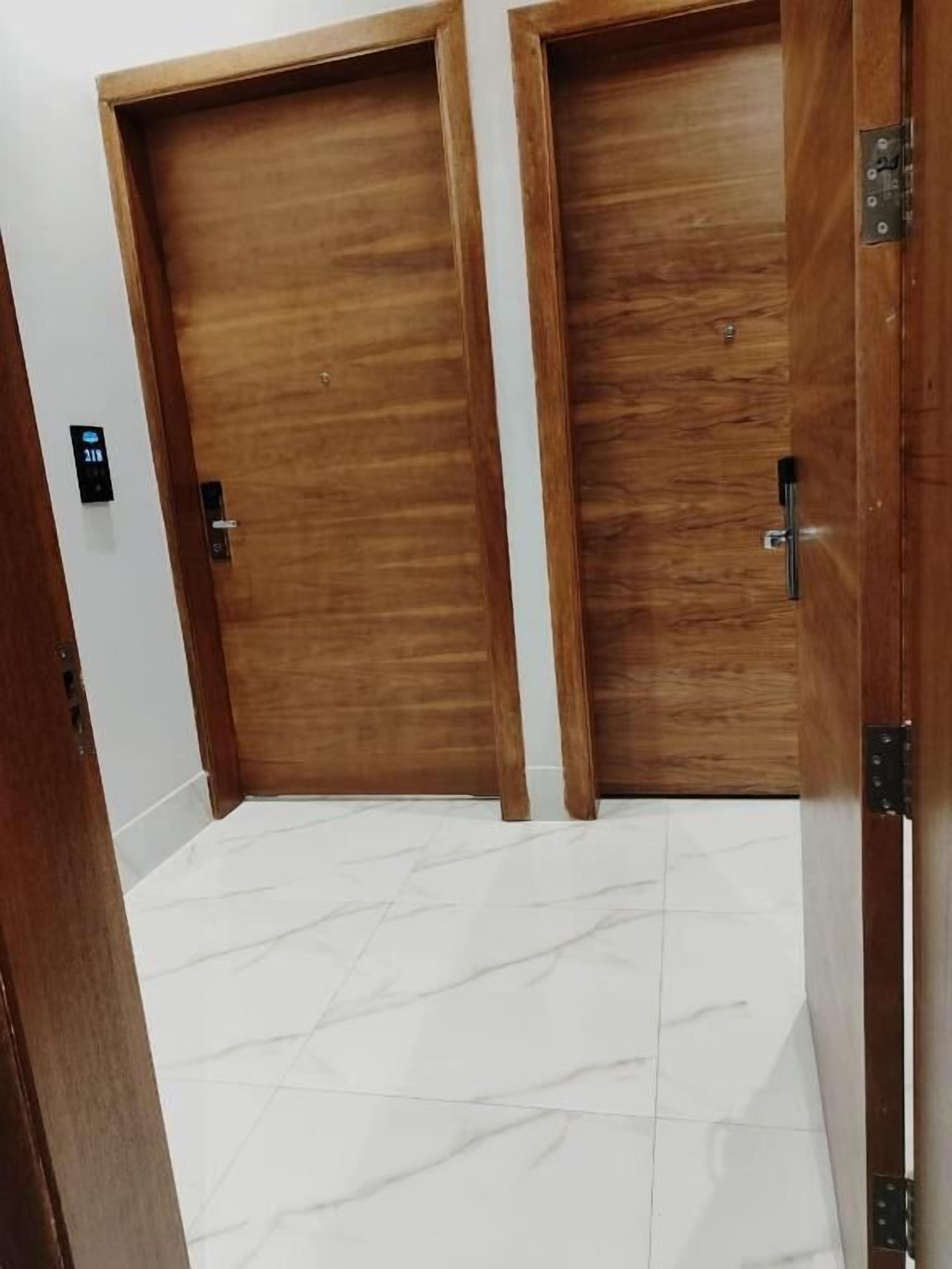 A hallway with two wooden doors and a white tiled floor.