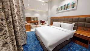 A hotel room with a large bed, a wooden headboard, a desk with a chair, and a bathroom area.