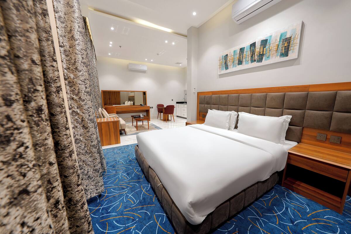 Une chambre d’hôtel avec un grand lit, une tête de lit en bois, un bureau avec une chaise et un espace salle de bain.