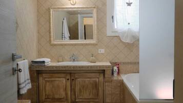 A bathroom with a sink, mirror, and toilet. There is a patterned rug on the floor.