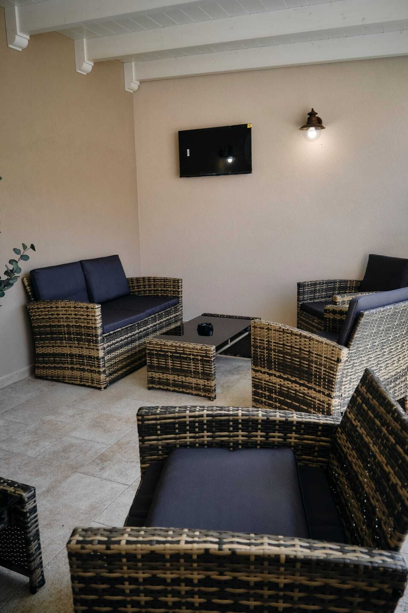 Quarto com móveis de vime, televisão de tela plana e luminária fixa na parede.