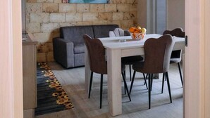Ein Essbereich mit Steinsäule, einem Gemälde, einer Couch und einem Tisch mit Stühlen.