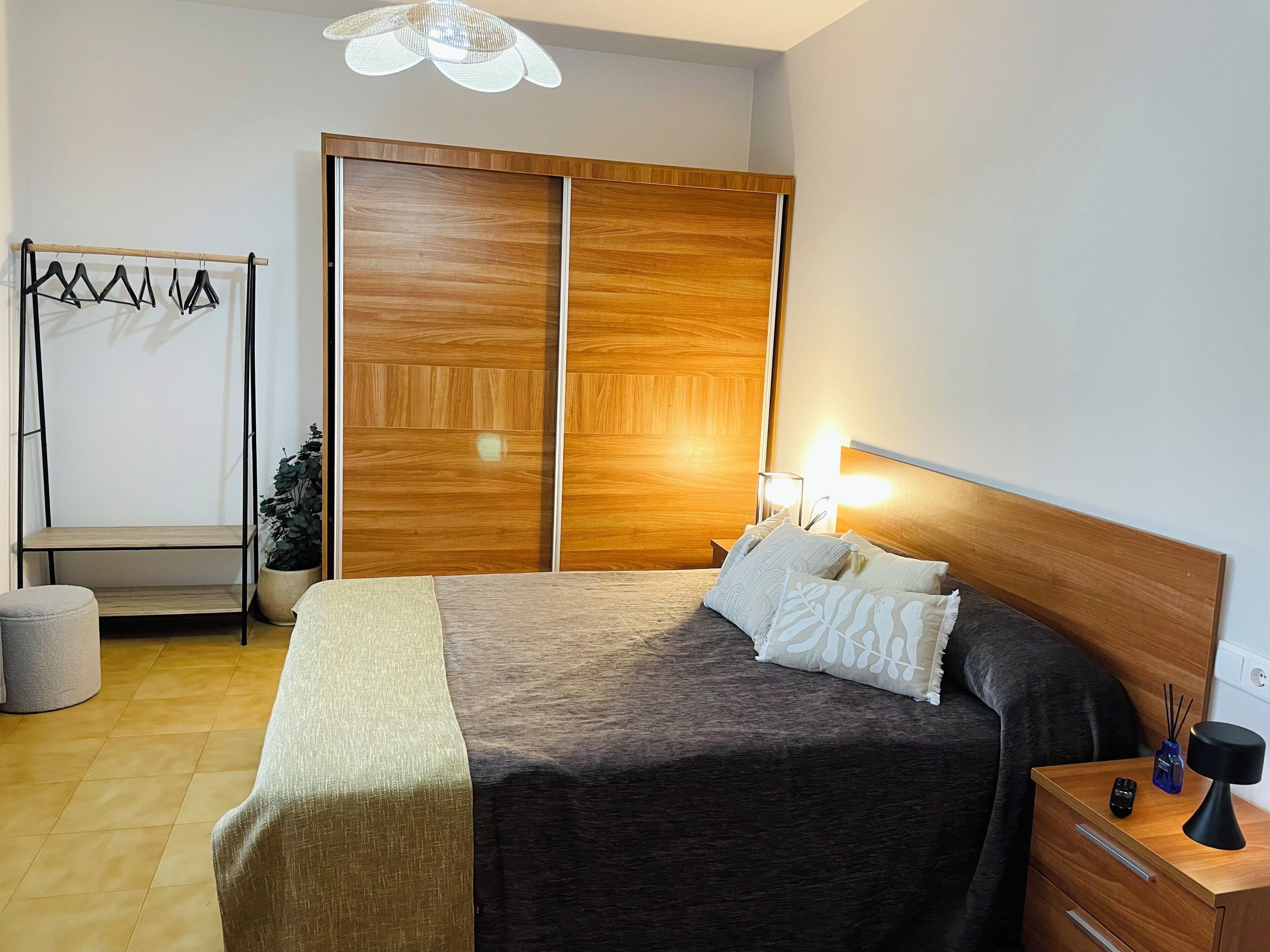 Ein Schlafzimmer mit Bett, Nachttisch, Lampe und Kleiderschrank.