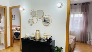 Una sala de estar con un mueble de entretenimiento negro, un espejo montado en la pared y una planta en maceta.