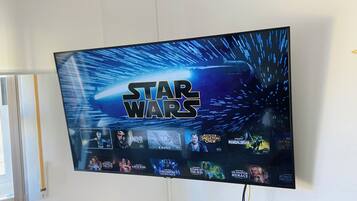 Ein an der Wand montierter Fernseher zeigt das Star Wars Logo und eine Auswahl an Star Wars Filmen.
