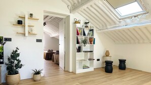 Una habitación amplia con suelo de madera, una estantería blanca y un tragaluz.