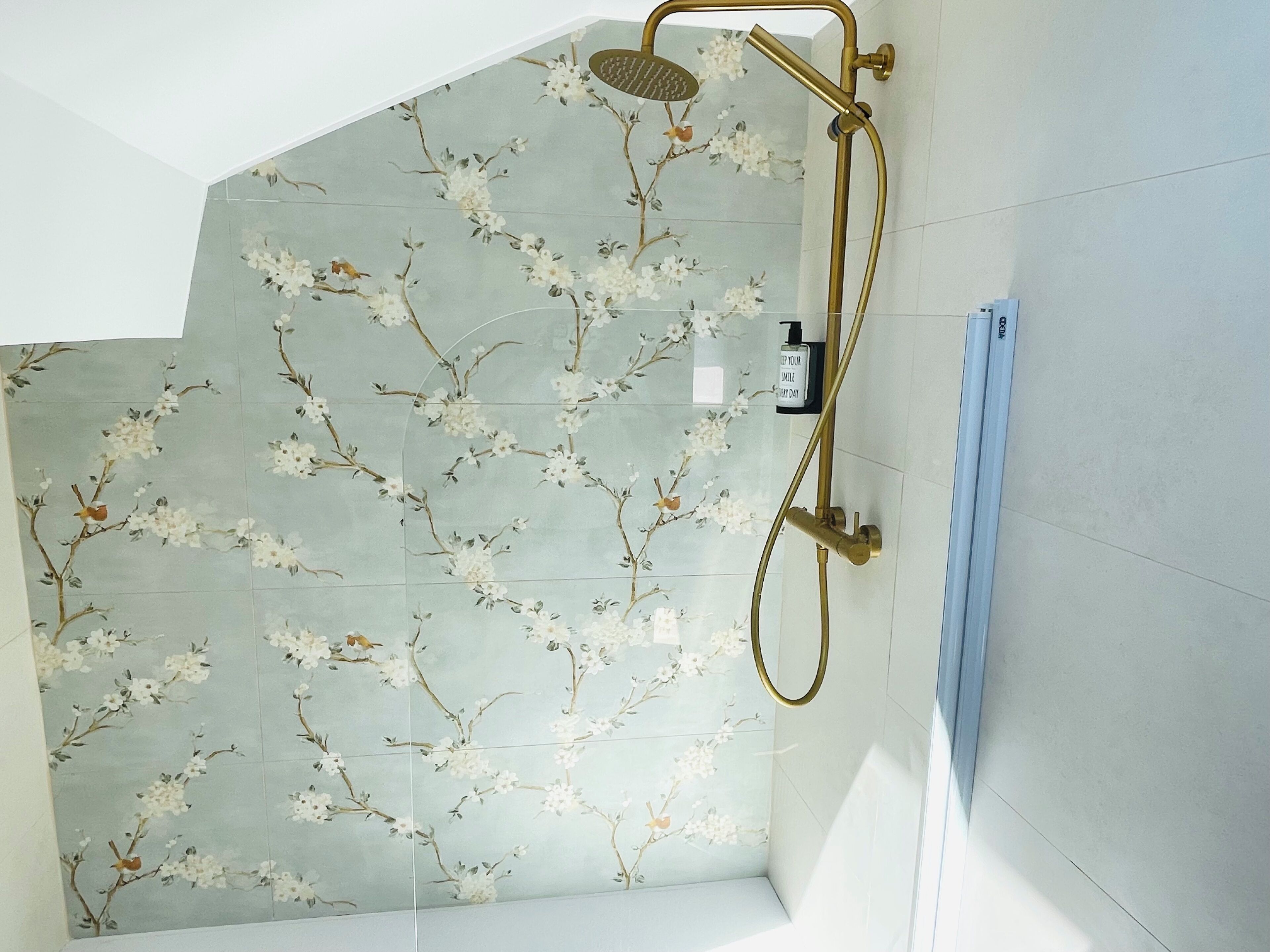 Ducha con diseño de azulejos florales y cabezal de ducha manual.