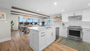 Une cuisine moderne avec des meubles blancs, un four encastré et un grand îlot central.