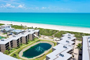 Un complexe hôtelier comprenant plusieurs bâtiments, une piscine centrale et offrant une vue sur la plage.