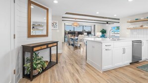 Une cuisine moderne avec des meubles blancs, un îlot central et un coin repas offrant une vue agréable.
