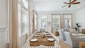 Un coin repas avec une table en bois dressée pour six personnes, entourée de chaises à motifs rayés.