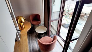 A corner of a room with a wooden floor, a round table, two red chairs, and a gold lamp. - Rempart Hotel (Diyarbakir)