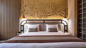 A modern hotel room with a large bed, two pillows, a nightstand with a phone, and a textured wall above the bed. - Rempart Hotel (Diyarbakir)