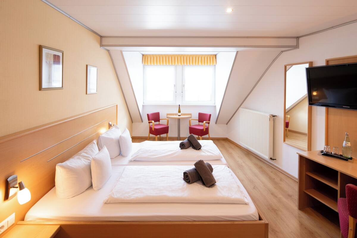 Een hotelkamer met een groot bed, een bureau, een televisie en een zithoek met stoelen.