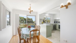 Een moderne keuken met witte kasten, een centraal eiland en een eethoek met een tafel en stoelen.