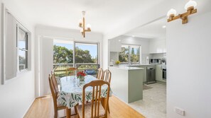 Una cocina moderna con armarios blancos, una isla central y una zona de comedor con mesa y sillas.