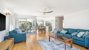 Un salón amplio con sofá, mesa de centro y zona de comedor con sillas y mesa.