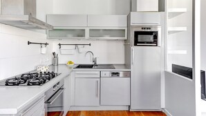 A compact kitchen with white cabinetry, a built-in oven, a dishwasher, and a gas stove. - Cozy 1BR Near Champs-Élysées - Sleeps 4 (Paris)