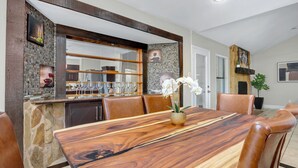 A dining area with a wooden table, leather chairs, a stone accent wall, and a kitchen in the background. - Checkmate and Chill-Inn I Yard Games, Families (Elgin)