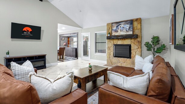 A spacious living room with a stone fireplace, leather sofas, a flat-screen TV, and a ceiling fan. - Checkmate and Chill-Inn I Yard Games, Families (Elgin)