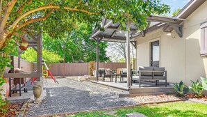 A covered patio area with outdoor furniture, a barbecue grill, and a pergola. - Checkmate and Chill-Inn I Yard Games, Families (Elgin)