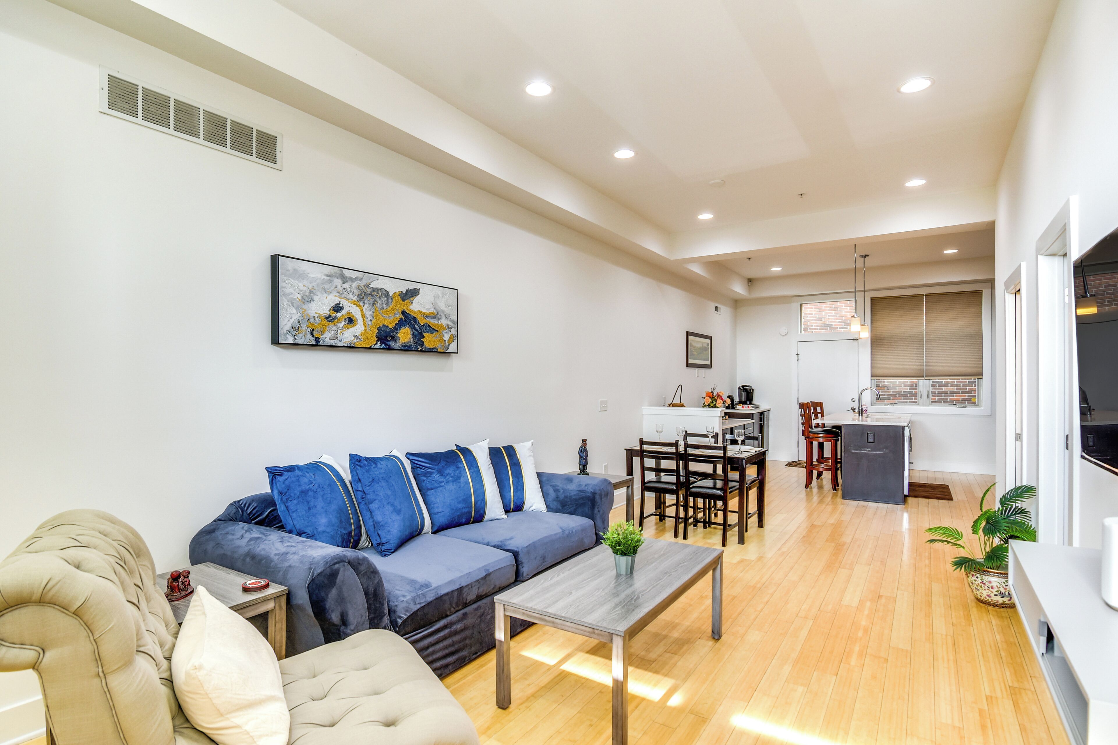 A modern living room with a sofa, coffee table, and a dining area with chairs and a table.