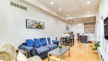 A modern living room with a sofa, coffee table, and a dining area with chairs and a table.