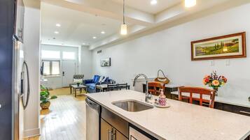 A modern kitchen with a large island, stainless steel appliances, and a dining area with a blue sofa and table.