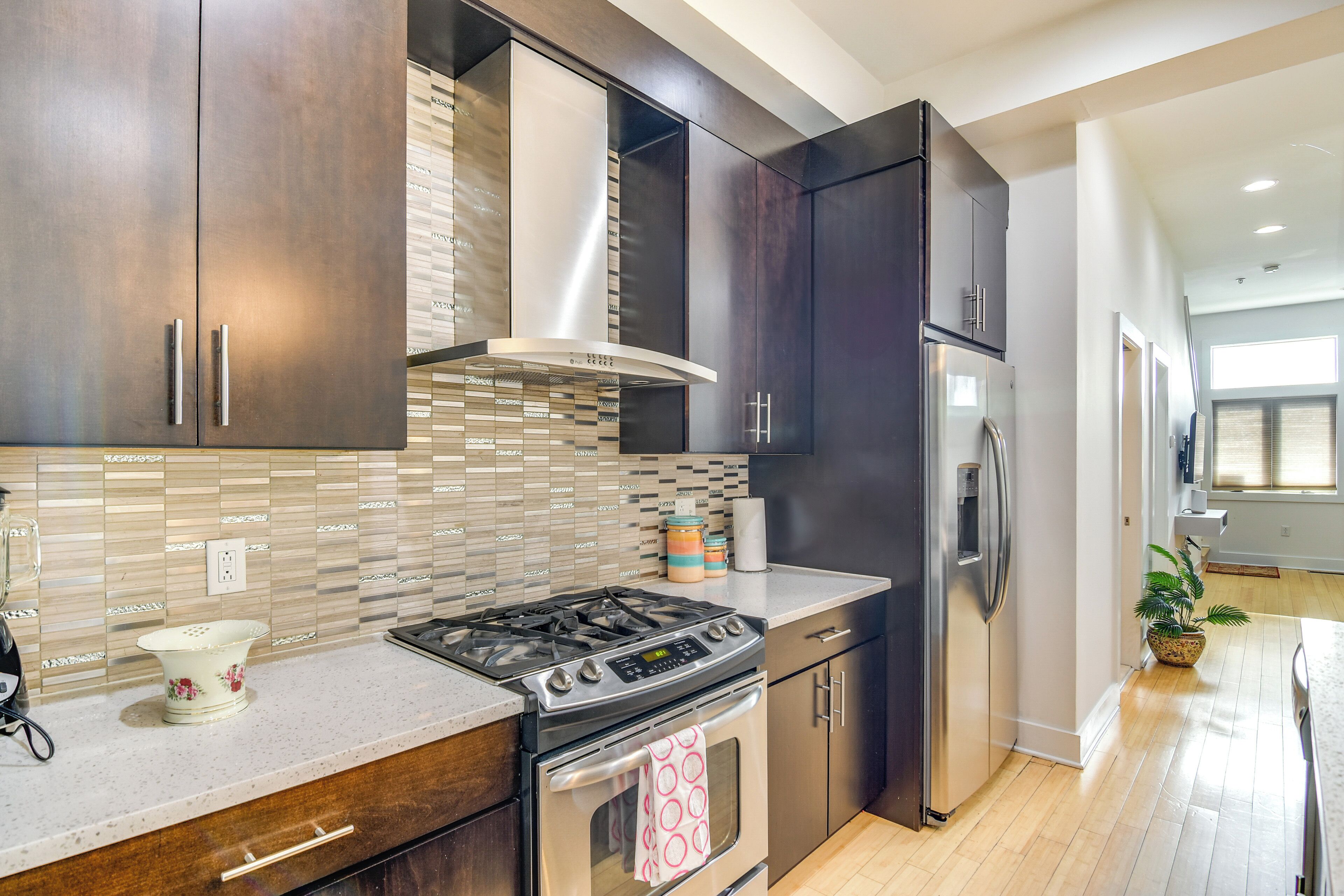 A modern kitchen with dark cabinets, a stainless steel stove, and a refrigerator.