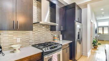 A modern kitchen with dark cabinets, a stainless steel stove, and a refrigerator.