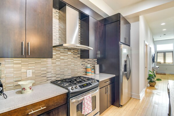 A modern kitchen with dark cabinets, a stainless steel stove, and a refrigerator.