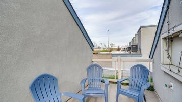 Un patio con dos sillas Adirondack azules, suelo de hormigón y vista a edificios al fondo.