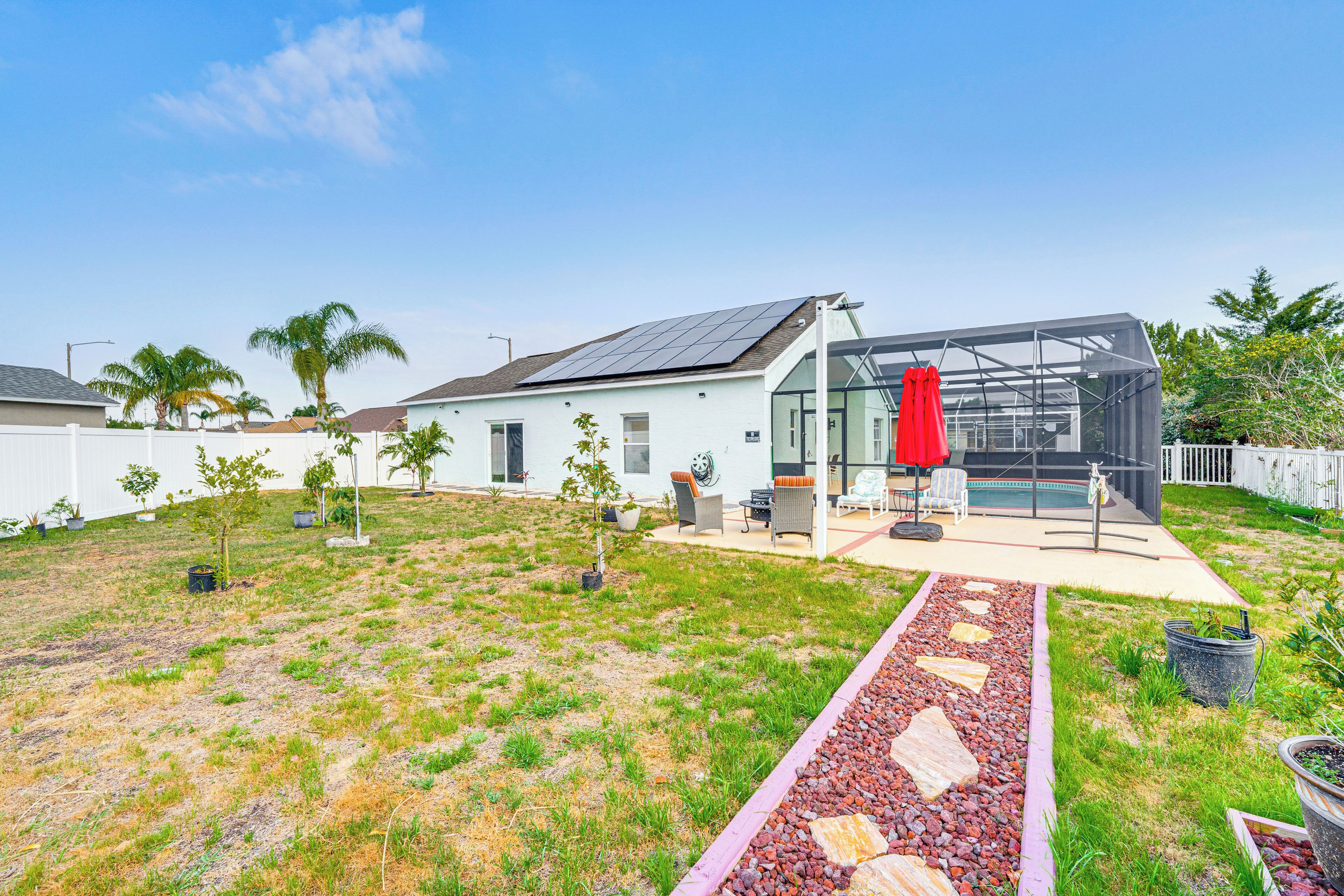 A modern house with a solar panel roof, a swimming pool, and a patio area with outdoor furniture.