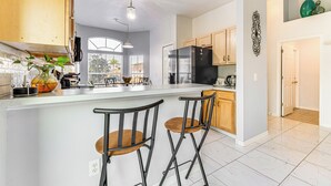 Een moderne keuken met een groot eiland, houten barstoelen en uitzicht op buiten.