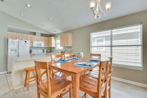 A modern kitchen with wooden cabinets, a central island, and a dining area with wooden chairs and a table. - 1 Mi to Shore: Home w/ Patio in Panama City Beach (Panama City Beach)