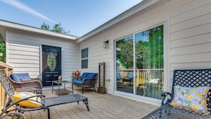 A covered patio with wicker furniture, a small table, and a door. - 3 Mi to Dtwn Entertainment: Pensacola Family Home! (Pensacola)